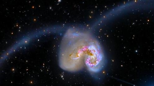 comma-shaped galaxy with two long trails of gas arcing away from the center